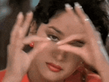 a woman in a red shirt is making a heart with her hands .