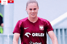 a female soccer player is wearing a maroon orlen shirt