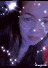 a close up of a woman wearing glasses with sparkles around her face