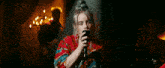 billie eilish is singing into a microphone while wearing a red shirt .