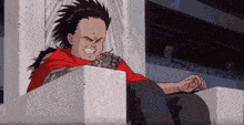 a boy in a red shirt is sitting on a concrete block .