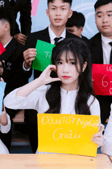 a girl holds up a yellow sign that says " dai tot nnghiep giau "