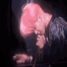 a woman with pink hair is singing into a microphone on a stage .