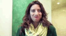 the woman is wearing a green sweater and a yellow scarf .