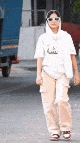a woman wearing sunglasses and a white t-shirt with arabic writing on it