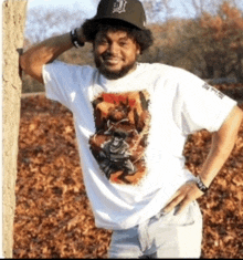 a man wearing a white shirt with a picture of a monkey on it is leaning against a tree