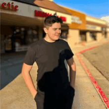 a man in a black shirt stands in front of a store that has the word chic on it