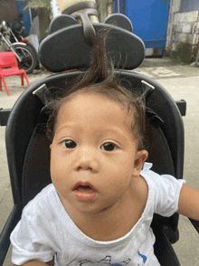 a baby is sitting in a stroller with a mickey mouse head rest