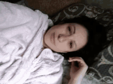a woman is wrapped in a pink blanket and laying on a bed .