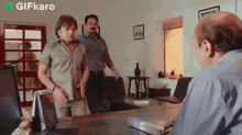 a group of men are standing around a desk in a room .
