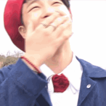 a man wearing a red hat and a blue jacket is covering his mouth