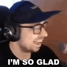 a man wearing headphones and a hat is smiling in front of a microphone and says `` i 'm so glad ''