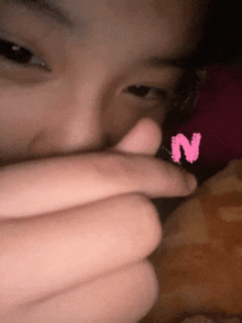 a close up of a person 's face with a pink letter n on it