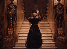 a woman in a black dress is standing on a set of marble stairs