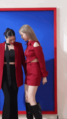 two women are standing next to each other in front of a blue wall .