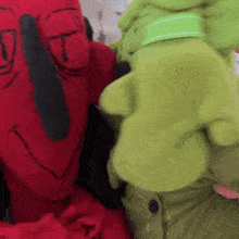 a red stuffed animal and a green stuffed animal are hugging each other