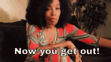 a woman is sitting on a couch with the words now you get out