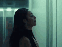 a woman in a black dress is standing in a hallway looking at the camera .