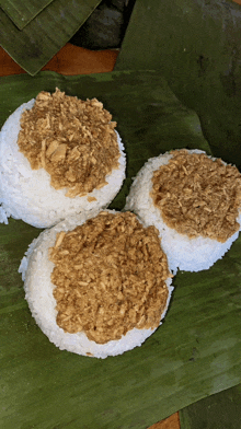three plates of rice with a brown sauce on top on a banana leaf