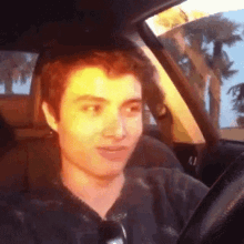 a young man is driving a car and making a funny face