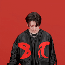 a young man wearing a black jacket with a red letter a on it