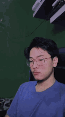a young man wearing glasses and a blue shirt is sitting in a chair