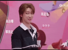 a man in a black shirt is standing in front of a pink background with chinese characters on it