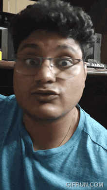 a man wearing glasses and a blue shirt has a gifrun.com watermark on the bottom