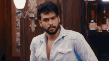 a man with a beard is standing in front of a bottle of alcohol