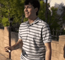 a man in a striped shirt is smiling and holding a cell phone