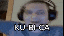 a close up of a person wearing headphones with the words ku-bi-ca written on the screen .