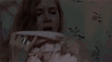 a woman is laying in bed with a pink blanket and a person is holding her breasts .