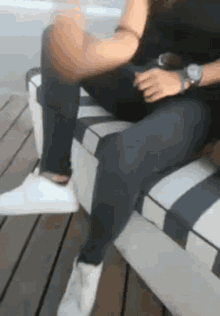 a woman wearing a watch is sitting on a bench