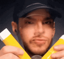 a man in a black hat is holding two yellow tubes