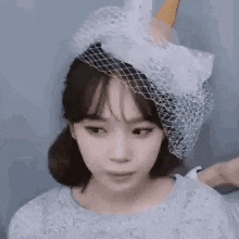 a close up of a woman wearing a white hat with a veil .