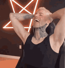 a man with tattoos on his arms and neck is sitting in front of a pentagram
