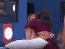 two women hugging each other in a blue room