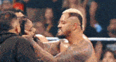 two men are wrestling in a ring and one of them is holding the other man 's head .