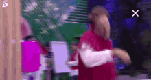 a man in a red shirt is dancing in front of a sign that says x on it .