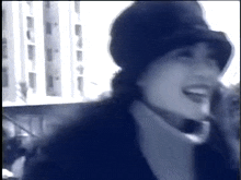 a woman wearing a hat and a turtleneck is smiling