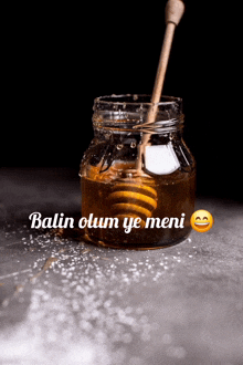 a jar of honey with a wooden dipper and the words " balin olum ye meni " below it