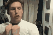 a man in a white shirt is looking at himself in a mirror .