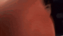 a close up of a person 's face with a red background and a blurred background .