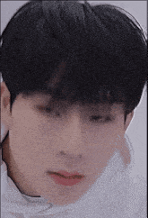 a close up of a young man 's face with a white shirt on .