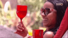 a woman is sitting in a chair holding a red wine glass and a cup .