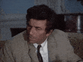 a man in a suit and tie is sitting in a room