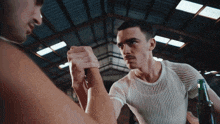 a man in a white shirt is holding another man 's hand