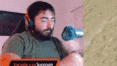 a man with a beard wearing headphones and a microphone is sitting in front of a wall .