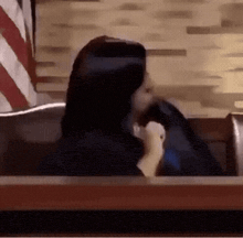 a woman is sitting in a judge 's chair holding a stuffed animal .