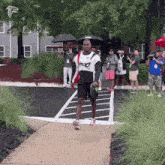 a man walking down a sidewalk wearing a shirt that says ' falcons ' on it